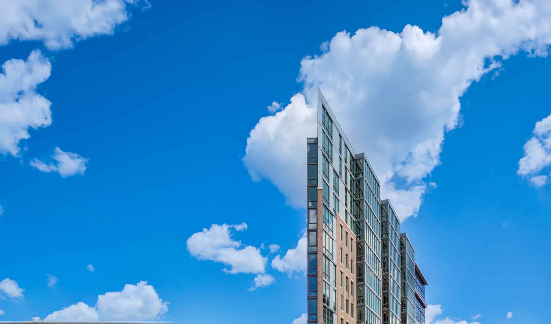 Exterior roofline of Pinnacle Apartments with blue sky and clouds