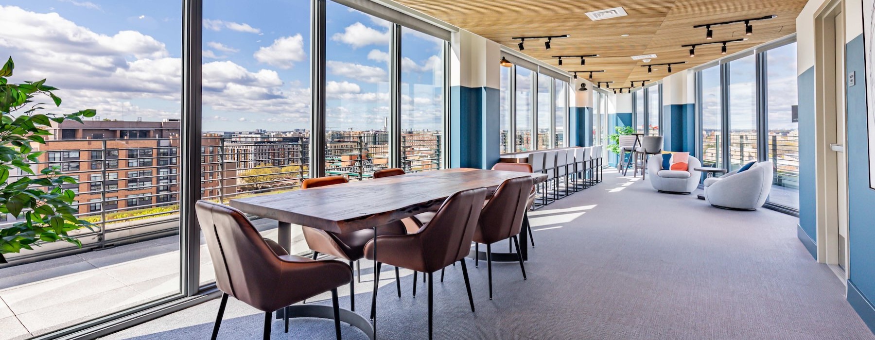 a clubroom with a table, chairs and windows