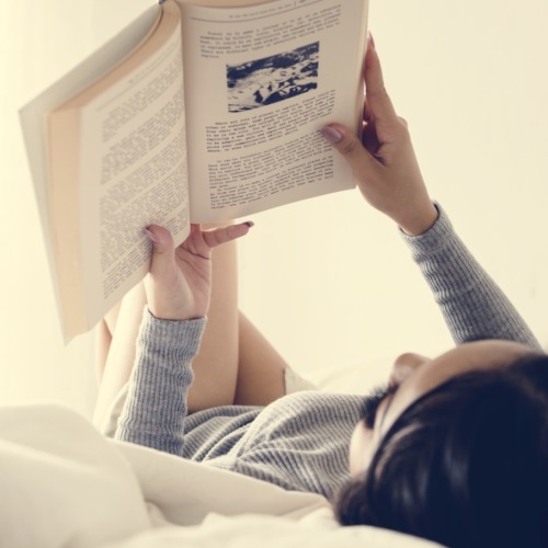 a woman reading a book on a bed